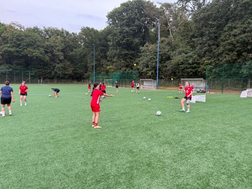 Fußballtraining auf einem Kunstrasenplatz mit mehreren Spielern in roten Trikots.